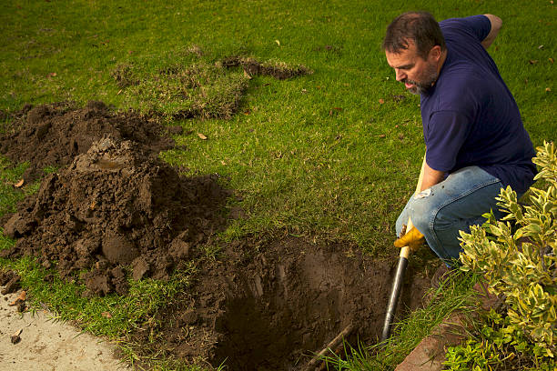 Sideview overhead of a adult man looking between 40-50 fixes a broekn water main pipe in his front yard by first digging with a shovel,as shown and then late finding the broken pipe and then reconnecting the broken PVC to the copper pipe;collection of shots showing the procress from start to finish