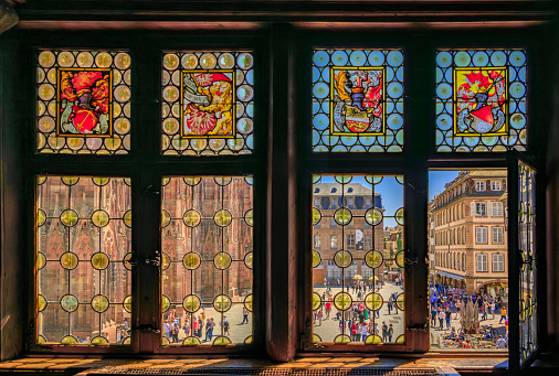 Strasbourg, France - May 31, 2023: Ornate Gothic facade of the Notre Dame Cathedral seen through stained glass window of Maison Kammerzell restaurant