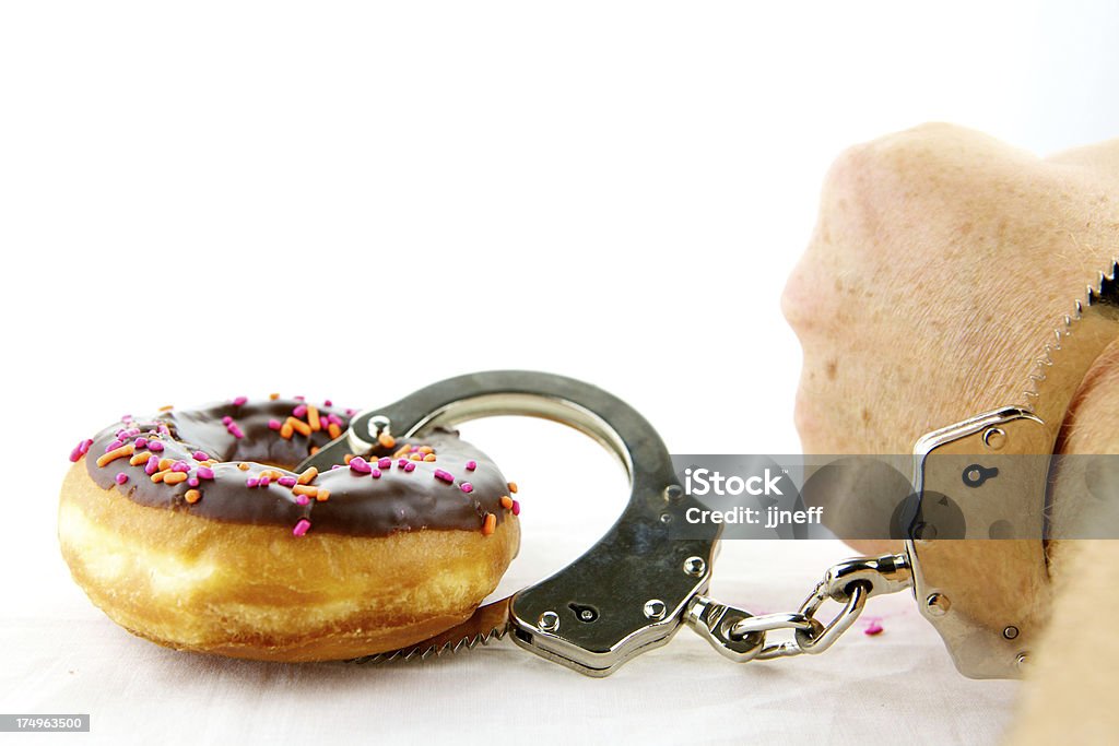 Addiction To Sweets Handcuffs with cuff around donut and the other around the wrist. This is about breaking addiction and being tied to habits. Addiction Stock Photo