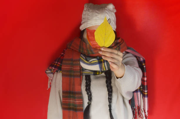 Close-up portrait of beautiful young woman with big yellow scarf on her head standing and looking at camera in autumn park