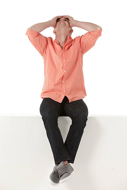 istock Young man sitting on a ledge with head in hands 174964286