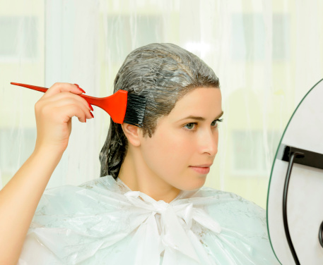 woman looking in the mirror and dying her hair.