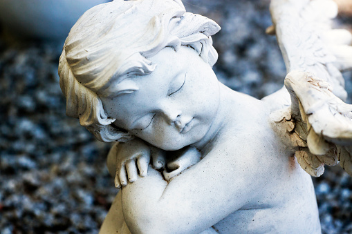 Closeup white statue of sleeping little angel - cherub, full frame horizontal composition