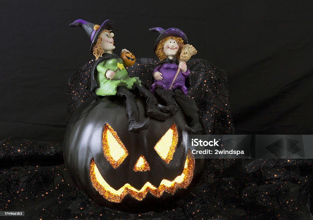 Witches on a Jack O'Lantern Two witches enjoy Halloween night on a lighted pumpkin. Anthropomorphic Stock Photo