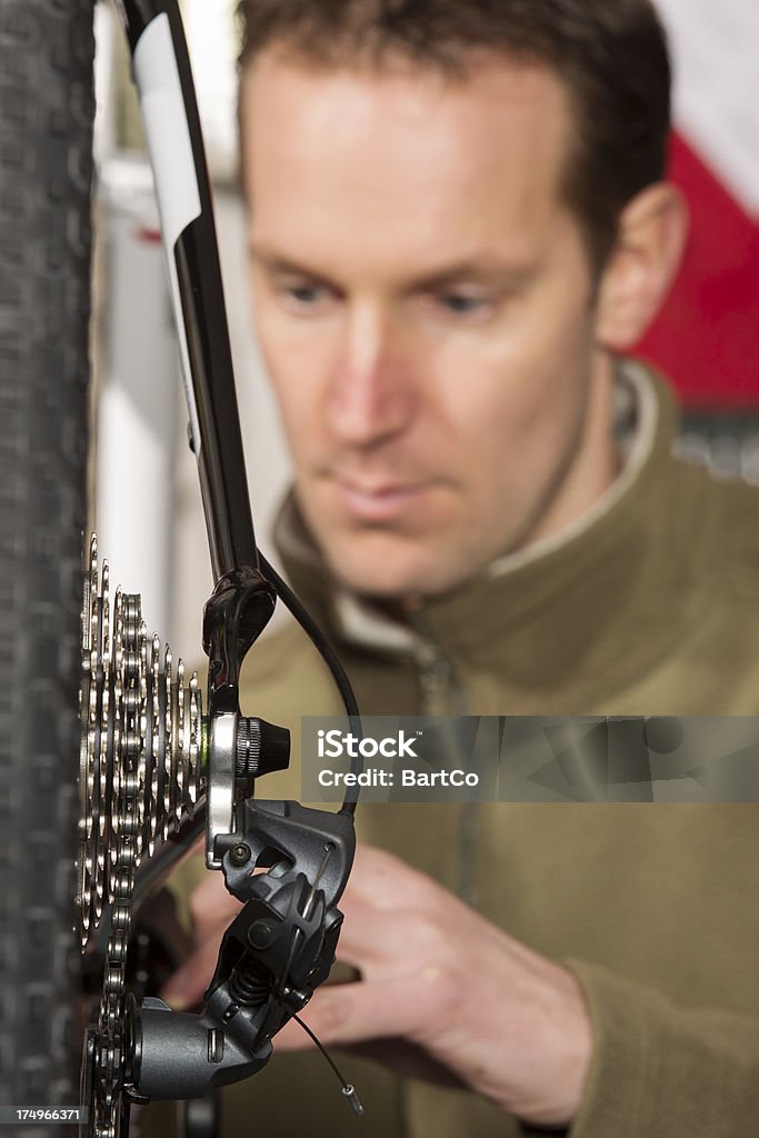 Uomo di riparare una bicicletta in negozio piccolo - Foto stock royalty-free di Adulto