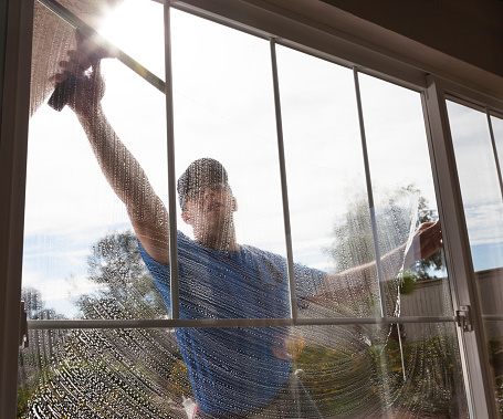 Man cleaning window of a home.