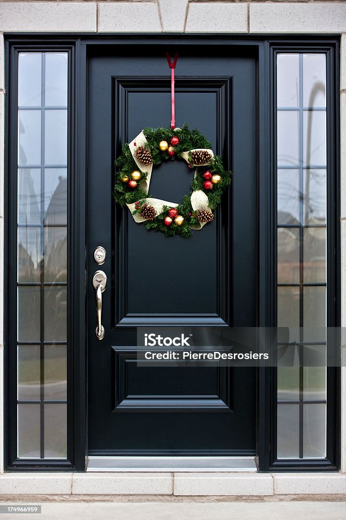 Christmas wreath on black door Christmas wreath hanging on black door of a house. Christmas Stock Photo