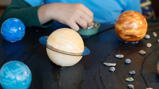 Close-up view of painted planets being assembled for a detailed solar system diorama, showcasing artistic precision