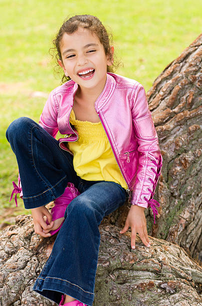 Little Girl Sitting on Tree with Big Smile stock photo