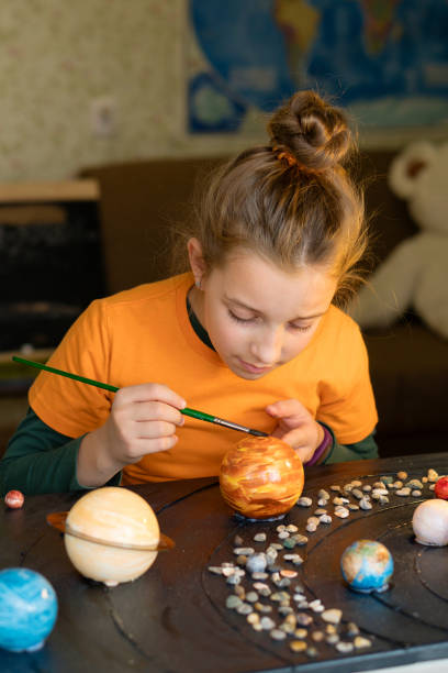 istock Young Astronomer Painting Celestial Orbs 1749684475