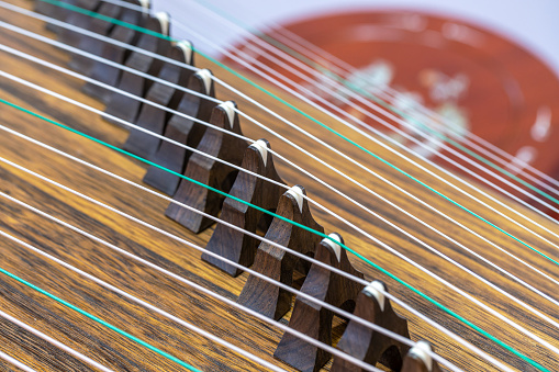 Close-up of strings on the fretboard of a bass guitar on a blurred dark background.