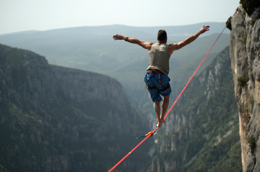 Man walking a 60 mt. slackline placed over the Verdon Gorges in France.