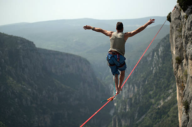 Man walking a slackline over Verdon Gorges, France Man walking a 60 mt. slackline placed over the Verdon Gorges in France. tightrope stock pictures, royalty-free photos & images