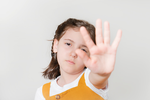 Serious little girl extend hand to block, tell to stay away, keep social distancing, rejecting and forbidding something. litttle girl gesturing stop.