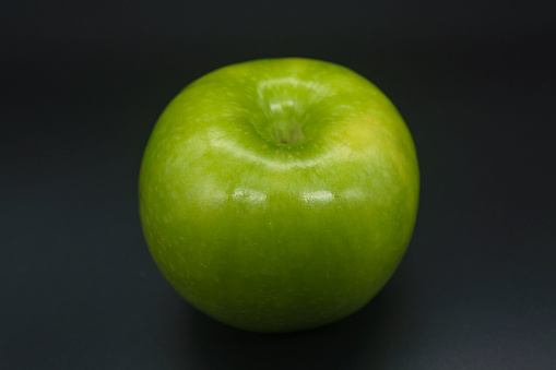 a green whole apple granny on a black background top view
