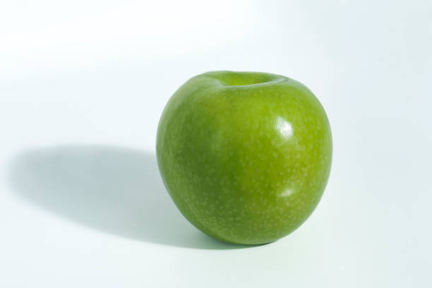 a green whole apple granny on a black background with shadow top view
