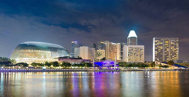 singapore skyline al atardecer de al otro lado de la bahía. - merlion singapore marina bay lighting equipment fotografías e imágenes de stock