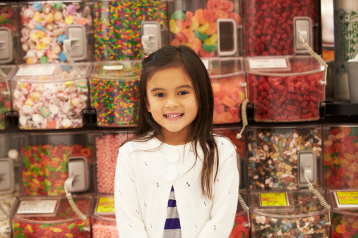 Girl At Candy Counter In Supermarket Smiling To Camera
