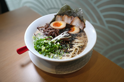 One Unhealthy serving of Spicy Instant Noodles in a Paper Bowl with a Plastic Fork