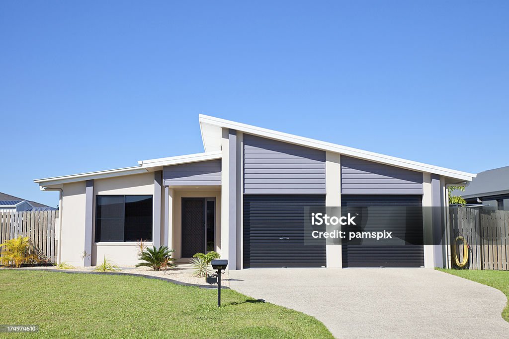 Affordable Home with clear blue sky copyspace Front of a simple neat and tidy new affordable single story residential home aa with green grass and clear blue sky. House Stock Photo