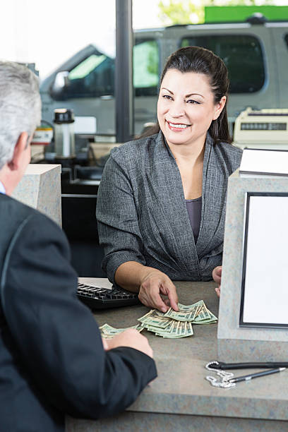 Smiling bank teller counting money stock photo