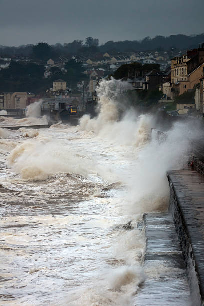 istock Waves breaking over railway track at Dawlish with train coming 174975382