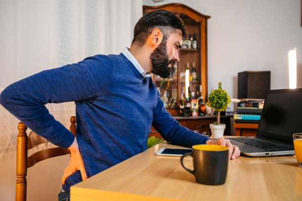 istock Young Male Writer Having Back Pain While Writing Using A Laptop At Home 1749757267