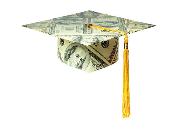 A graduation mortar board cap made with US currency money, cut out and isolated on white background. One hundred dollar bills pattern with tassel, for concepts of education costs, university finances, saving for college tuition, and job training expenses, as well as achievement, success, and value of a higher degree.