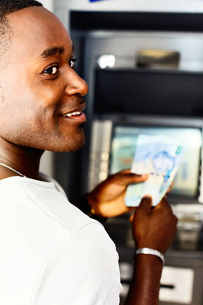 homem sorridente withdraws dinheiro de dinheiro máquina - currency spending money african descent black - fotografias e filmes do acervo