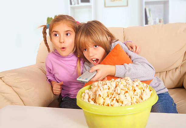 istock Boy  and little girl with popcorn watching television 174976802
