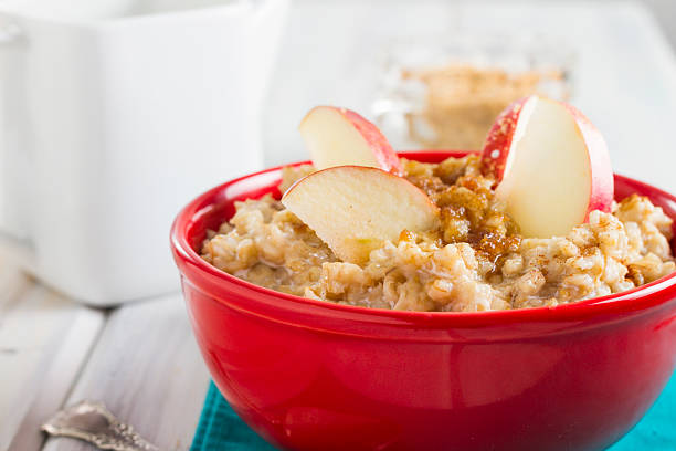 Red Bowl Of Hot Oatmeal With Blueberries and Apple Slices stock photo