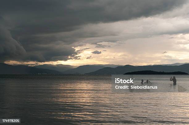 People Swimming In Ocean On Evening With Tropial Storm Background Stock Photo - Download Image Now