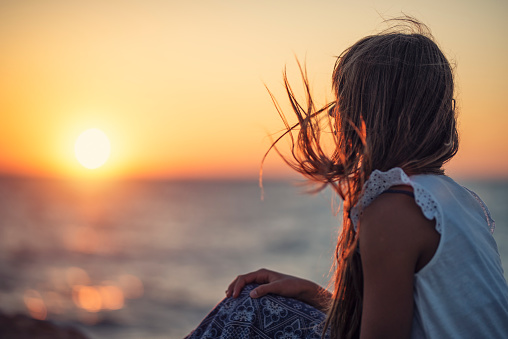 Little girl looking at the beautiful sunset over the sea.\nShot with Nikon D810