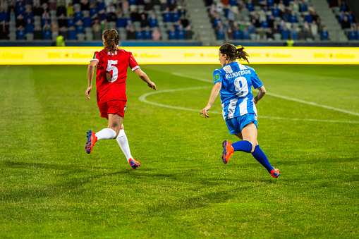 Female football players running on field during match back view