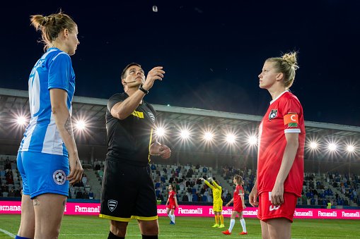 Soccer referee and female team captains meeting in field center and flipping coin medium shot