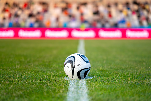 Close-up of a Leg in a Boot Kicking Football Ball. Professional Soccer Player Hits with Fierce Power, Scores Goal, Grass Flying. Football Championship Concept. Low Angle Ground Artistic Shot.