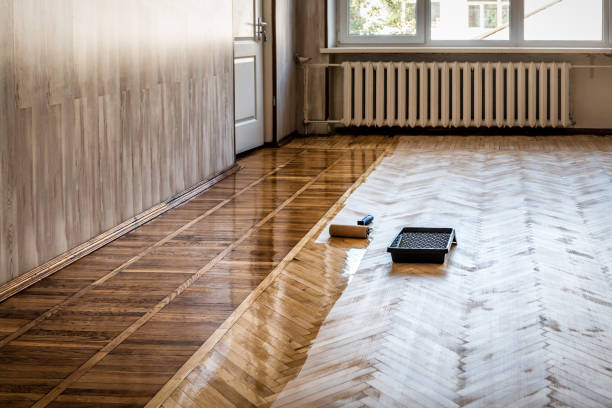 Lacquering wood floors. A roller to coating floors. Varnishing lacquering parquet floor by paint roller - second layer. Home renovation parquet stock photo