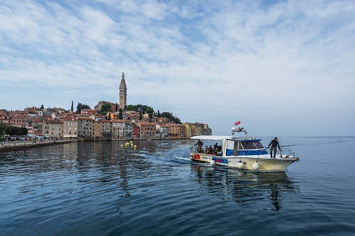 Rovinj, Croatia - October 10, 2023: A diving boat docks at the shore, with the old town of Rovinj in the background