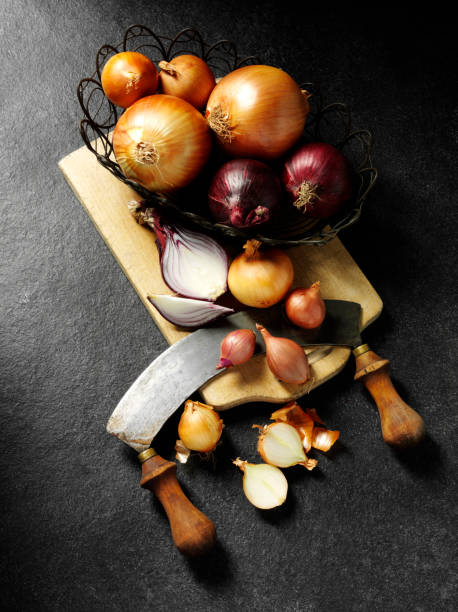 Group of Different Onions A group of different onions from the onion family on a wooden chopping board with a antique knife on a dark slate background.Click on the link below to see more of my fruit and vegetable images mezzaluna stock pictures, royalty-free photos & images