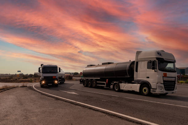 istock Two tankers with dangerous goods, one parked and one driving under a dramatic sky at dawn. 1749798626