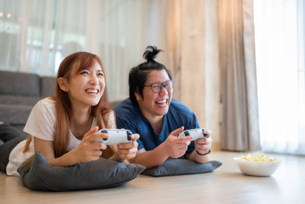 istock Asian couple lying on on the floor playing video game 1749812631
