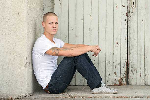 istock pensive young man sitting on the ground 174981376