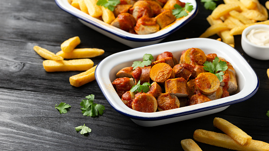 Traditional German currywurst, served with potato chips and sauce.