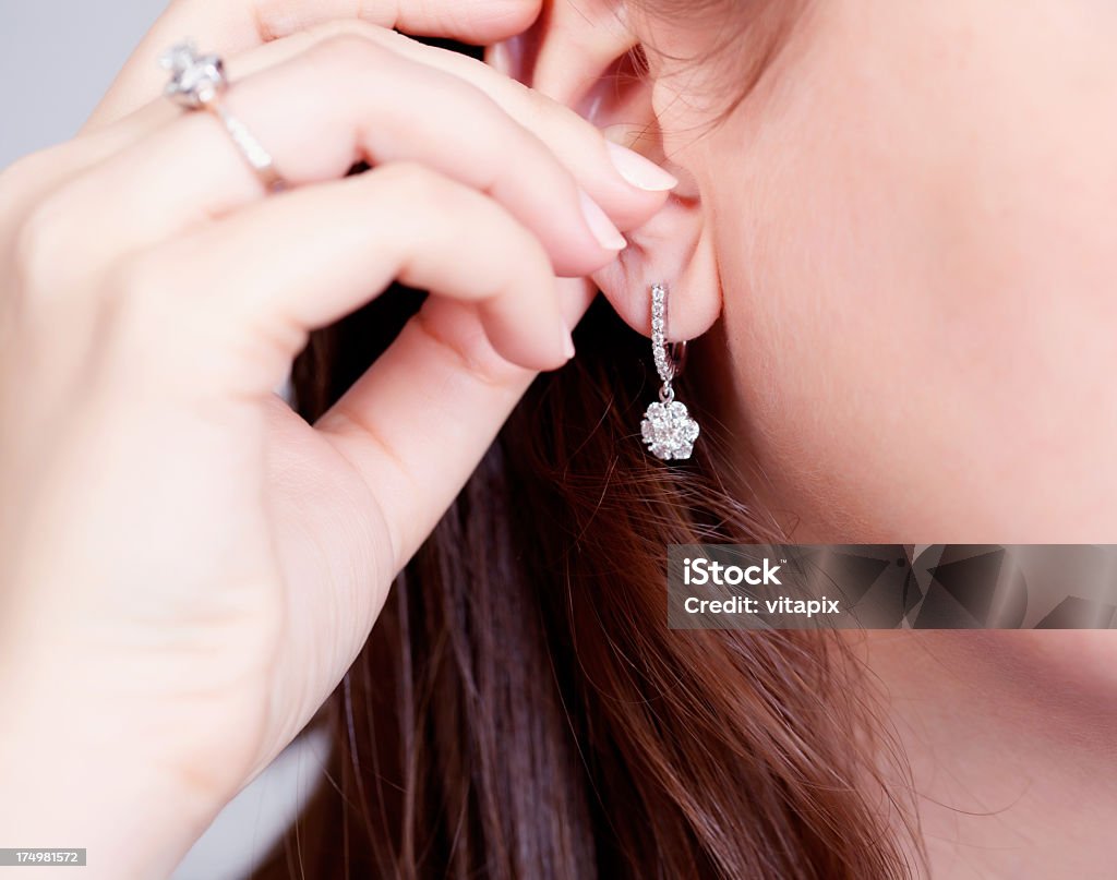 Diamond Accessories Woman putting on diamond earrings Earring Stock Photo