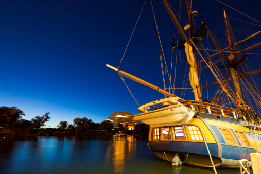 Late evening View across Sacramento River at West Sacramento Ziggurat building and a sail boat in a forefront.