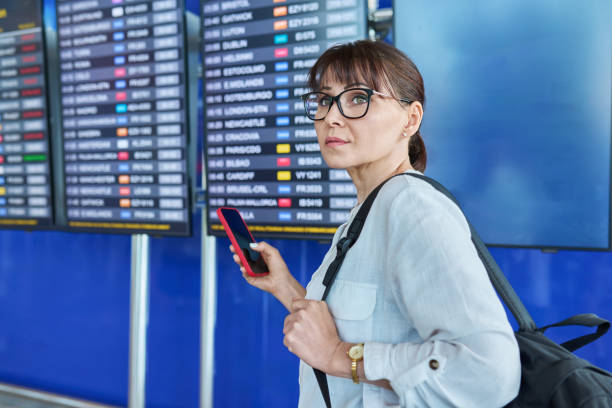 istock Woman passenger looking at flight schedule board at airport 1749848156