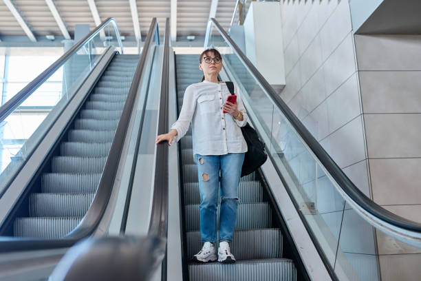 istock Middle-aged woman with backpack in casual style on escalator 1749848171