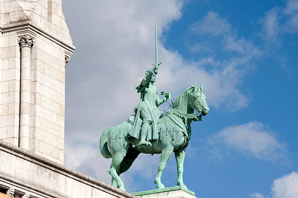Equestrian statue of Jeanne d'Arc with sword risen in Strasbourg France enlightened by spotlight throwing shadow on facade of Eglise St Maurice