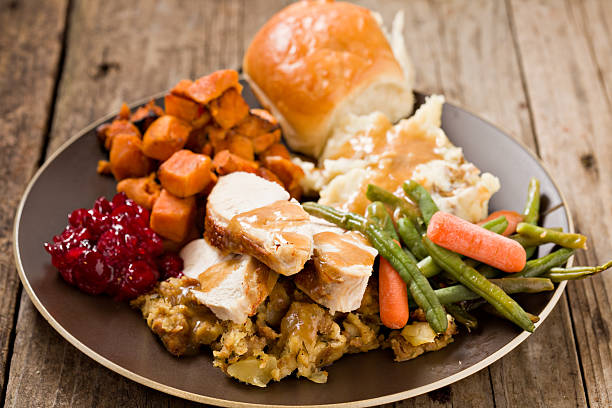 Turkey Dinner Plate. A high angle close up shot of a brown plate containing a bountiful thanksgiving turkey dinner. Shot on a grungy old wooden table. thanksgiving full stock pictures, royalty-free photos & images