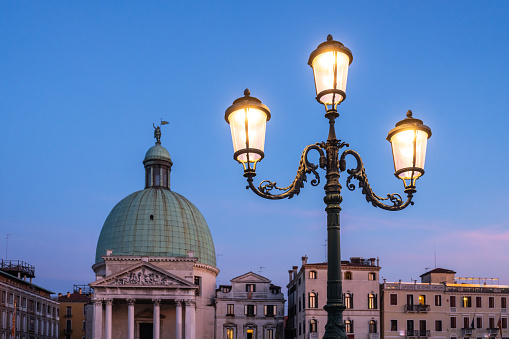 Lantern illuminated on a night in Venice, in the background the Church of San Simeon Piccolo.